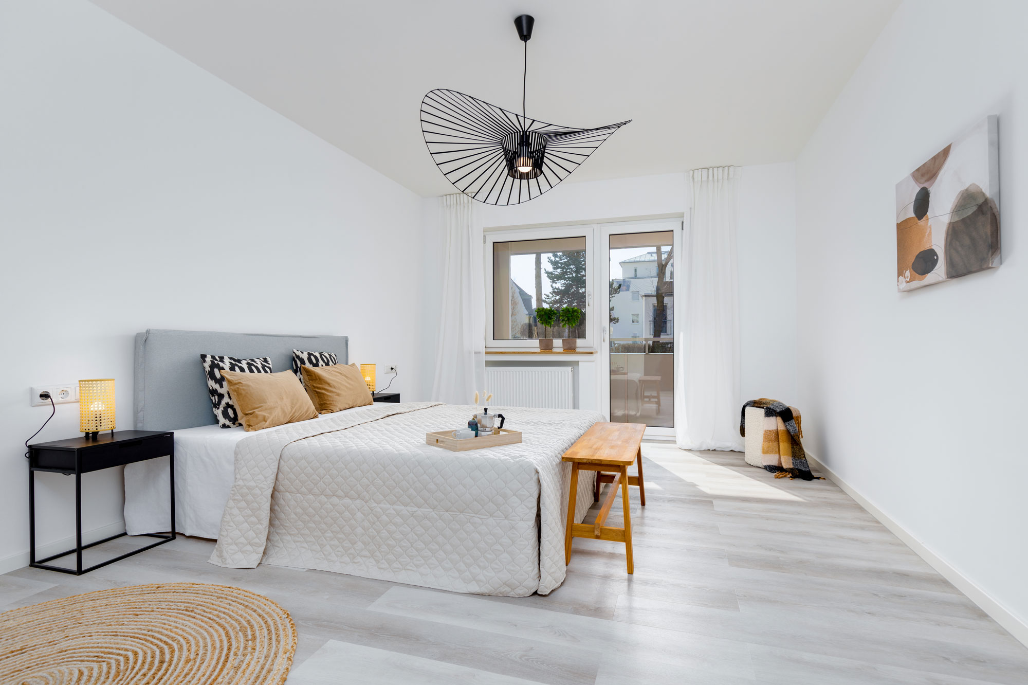 Ein von elements Home Staging aufgewertetes Schlafzimmer, mit stilvoller Lampe, einladendem Bett und Möbeln.